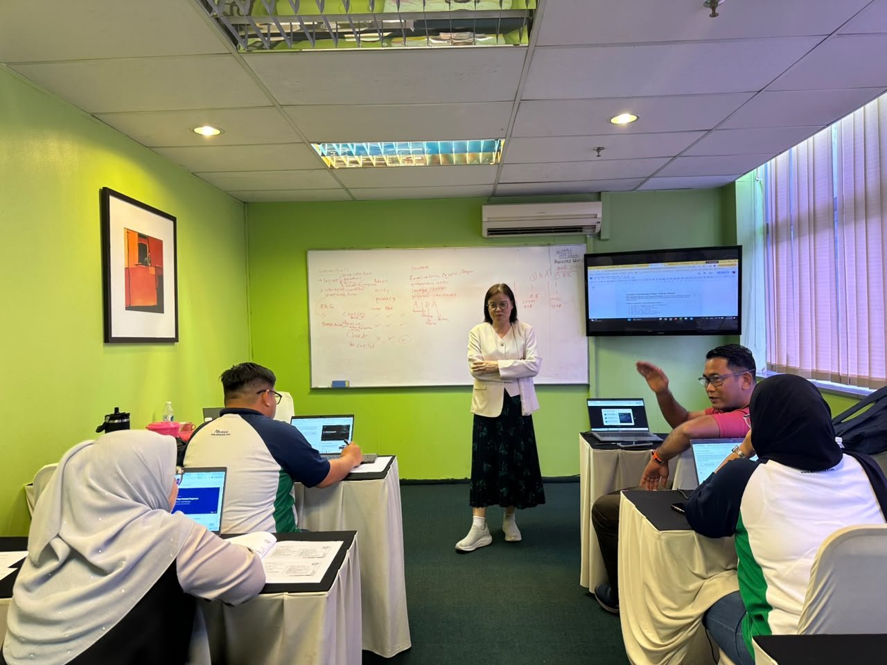 Participants working together on laptops during a hands-on workplace AI training session